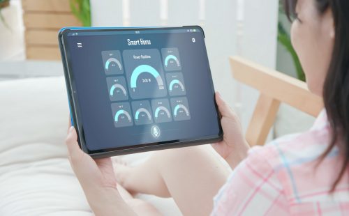 Iot Smart Home Concept - rear view of asian woman ask digital tablet to show all the electric meter in house by voice at home