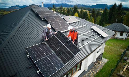 Engineers building photovoltaic solar module station on roof of house. Men electricians in helmets installing solar panel system outdoors. Concept of alternative and renewable energy. Aerial view.